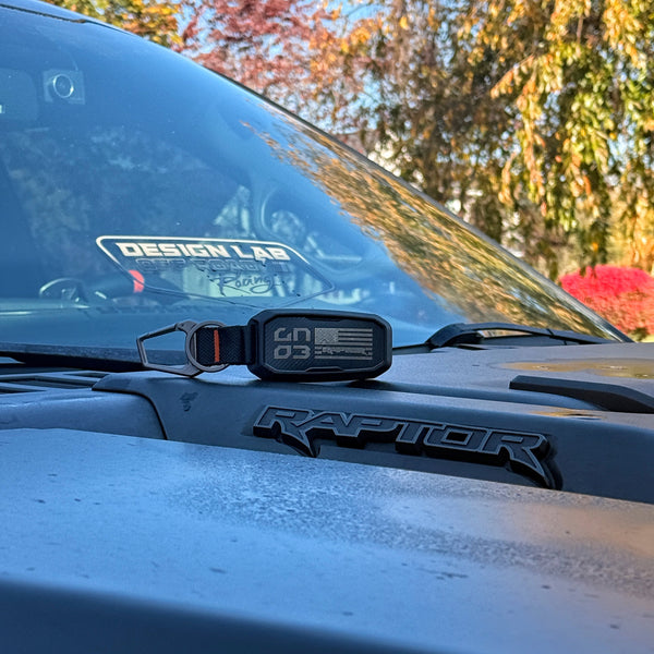 Ford Raptor car with a digital display on the hood, surrounded by trees with autumn foliage.